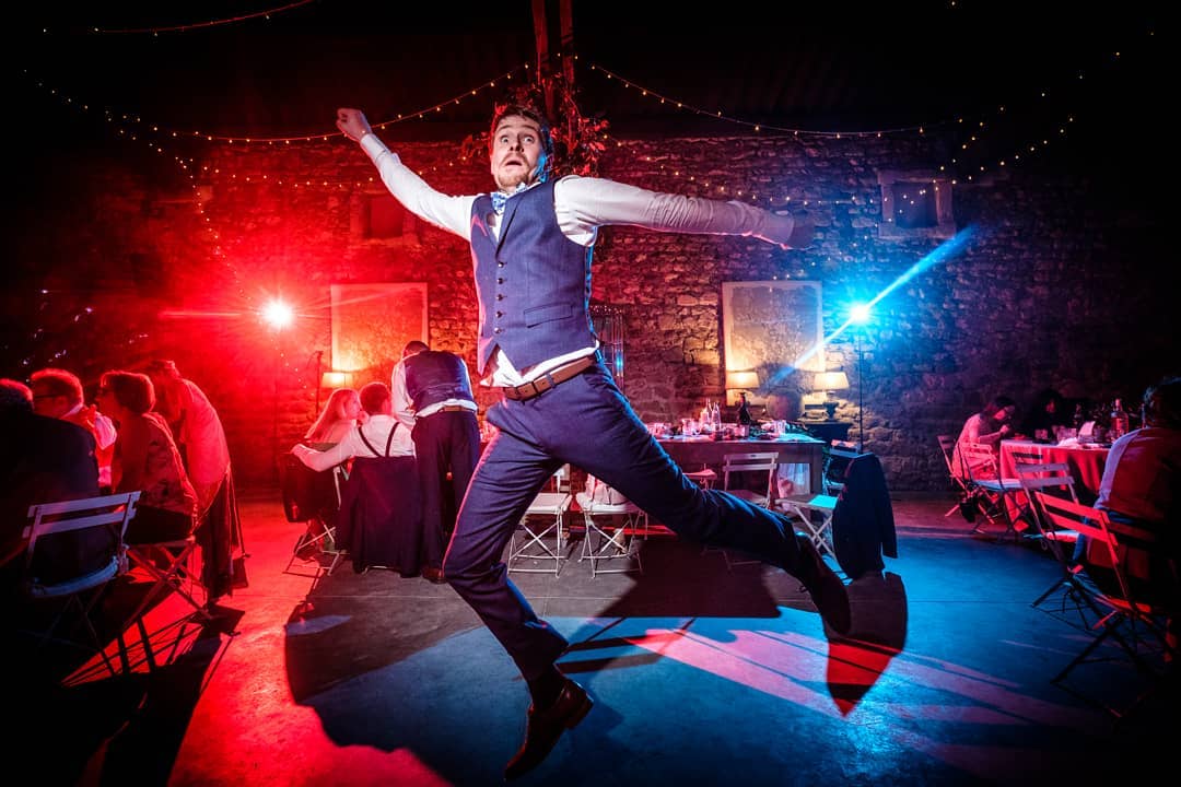 Invité sautant sur la piste de danse, ambiance de soirée dansante en lumières rouge et bleue lors d'un mariage Love & Live